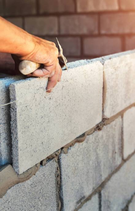 Worker building wall bricks with cement